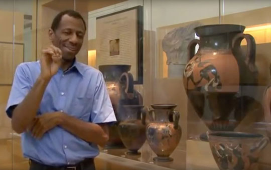 Man signing in ASL next to a display of jars.