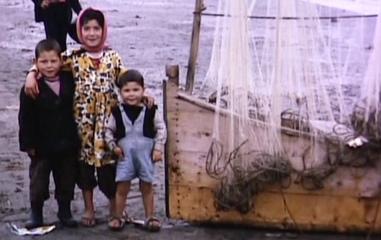 Children standing next to a fishing boat.