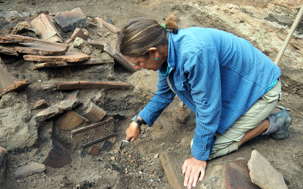 A person clearing small pebbles from around a sherd.