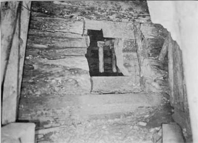 A rough hewn rectangular doorway cut into a stone wall.