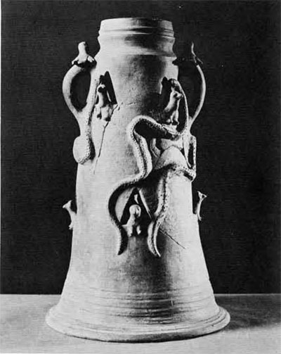 Conical object with two small handles, decorated with snakes and people looking out of windows.