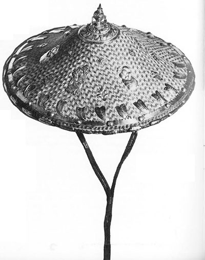 A city hat. Pagoda-shaped, twillwork. Covered with silver flowers and leaves, topped with a silver finial. Purple cotton cord forms a long adjustable chin strap with silver bands and ornaments where attached to underside of hat.