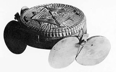 Flattened pill box shaped hat of woven rattan with pearl shell plates on either side.