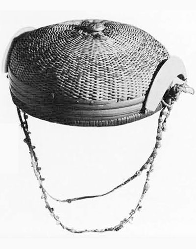 Rattan wicker hat with red and black decoration; red bands at border; braided string strap with beads; brass button with American eagle in center on crown; split boar's tusk at each side.