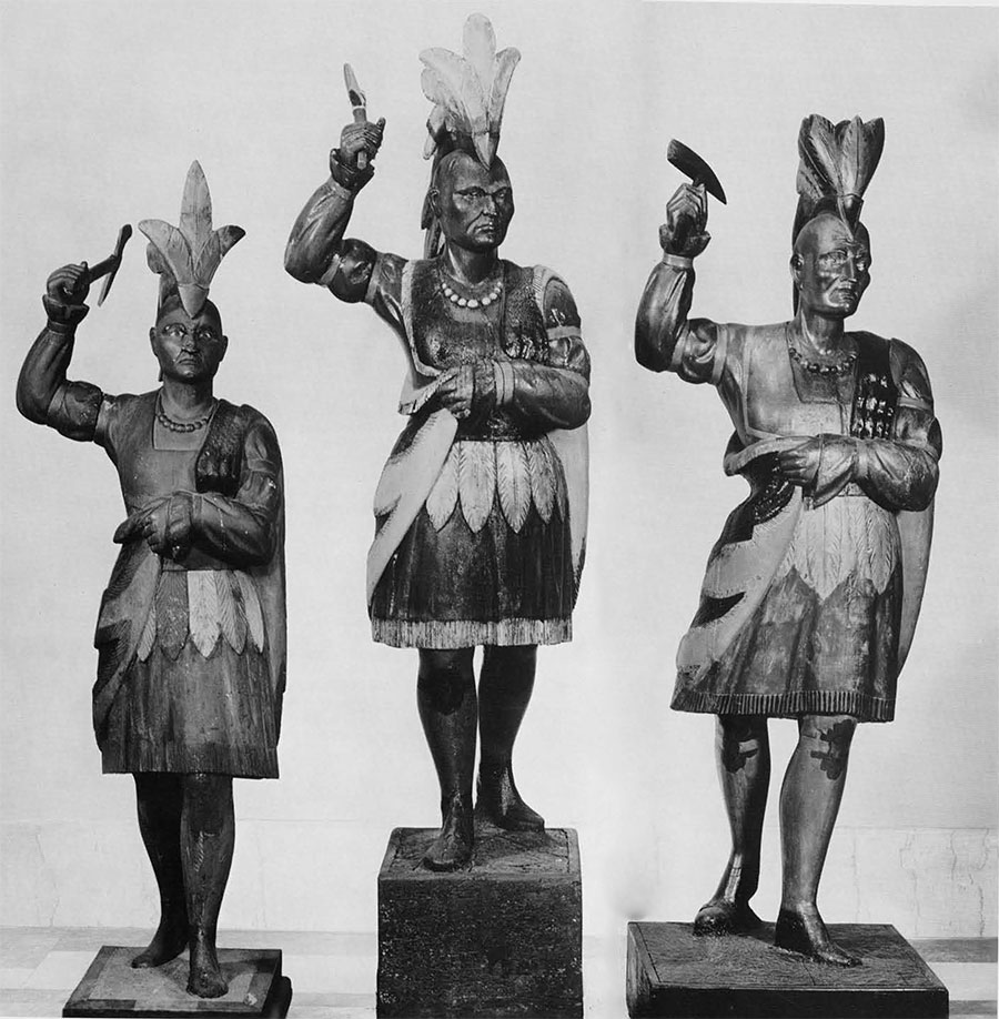 Three Indians with Tomahawk. The one at the left from the White Collection, lent by Mrs. James Reswick, the other two lent by Mr. Alfred E. Bissell. Heights: 64 inches, with base 71 inches. 66 inches, with base 84 inches; 67 inches, with base 77 inches. According to Jean Lipman in her book on American folk art, The Indian at the left is one of the few known to have been made by a figurehead carver, John L. Cromwell. Characteristic of the work of the figurehead carver, are the windblown cloak and headdress and the slightly uplifted face with an outward searching gaze. It is conceivable that the other two figures are also the work of Mr. Cromwell; certainly they must have come from his workshop. The only differences are the slightly larger scale and and variations in the tobacco-leaf kilt. Two more examples are known from photographs, and one Indian figurehead said to have been made about 1836 and later used as a Cigar Store Indian is also identical to these others. 