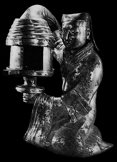 Gilded bronze figure of a palace servant girl carrying a lamp, discovered in Tou-wan's coffin chamber. The side pieces are movable so that the opening can be reduced and the shaft of light directed towards a beautiful object. The hood running into the sleeve of the girl conceals a funnel thus causing the lampblack to be collected in the cavity of the figure, preventing it from dirtying the environment. The girl's head and the hood are detachable for easy cleaning. Nine short inscriptions in different places record the names of owners of palaces in which the lamp was kept. Western Han between 179-151 B.C. Height 47.5 cm. Wên-wu 1972. No. 1. Pl. 1.