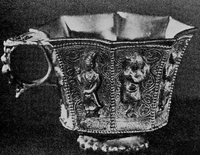 Among the precious objects hidden in the pottery jars discovered in 1970 in Hou-chia-ts'un, southern suburb of Sian (formerly Ch'ang-an), province of Shensi, was this octagonal stem cup (with a handle) made of solid gold. Each panel contains the figure of a musician or dancers in repoussé on a background of winding plant tendrils. The long noses and the costumes of some of these men show that they represent non-Chinese performers. T'ang dynasty, first half of 8th century A.D. Height, 5.5 cm. 
