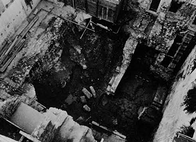 A view of excavations by the eastern perimeter wall of the palace (cf. pp. 30-31 #2) at the end of 1972. Part of the house in the background had been demolished: what remains stands on Roman walls. Rerouted water pipes, sliding earth from medieval fill, and water seepage on the lower levels can be seen. 