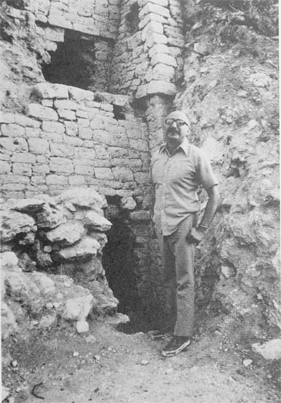 Victor Segovia, Mexican archaeologist, stands in front of holes dug by looters in side of Maya pyramid at Kohunlich, remote jungle site in Quintana Roo area of Mexico (on Yucatan peninsula)