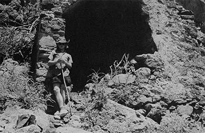 A man leaving against the entrance of a cave.