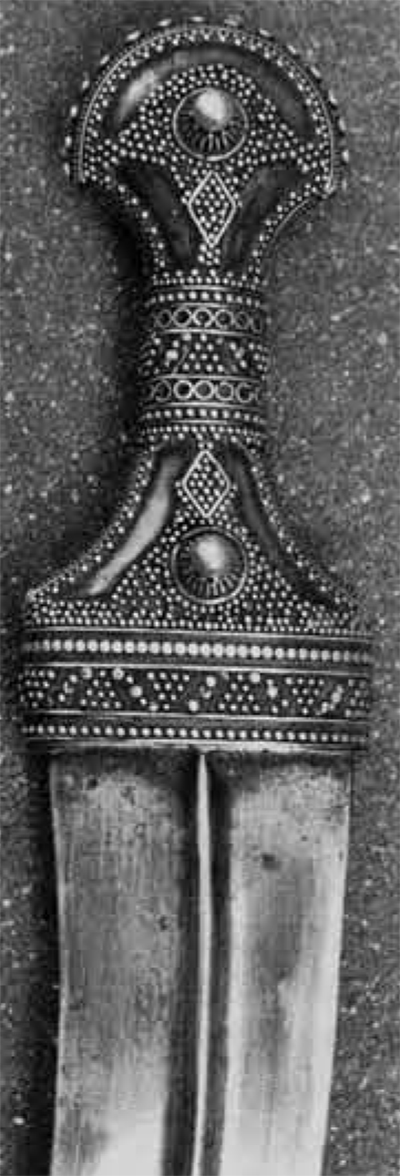 Close up of an ornately decorated hilt of a dagger.
