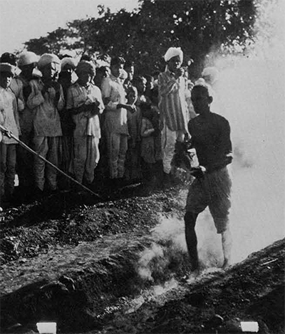 A man walking over hot coals while a crowd watches.