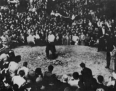 A large crowd of people gathered around and watching a firewalker.