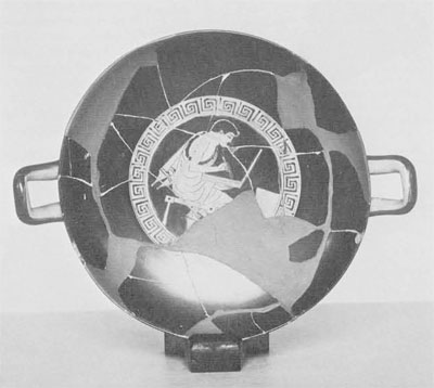 Kylix that has been pieced back together from fragments, interior depicting a youth seated on stool writing on tablet in the center, view looking down into the kylix.