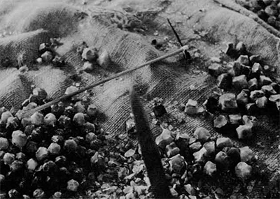 Spike anvil in the foreground; a light "second stage" chipping hammer on the floor along bead forms and detritus