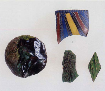 Left: The glass ball (MS5566), with its interior revealed by a modern break. Note the air bubbles that were trapped between the re-fused pieces of glass. Upper right: A fragment from the rim of a straight-sided mosaic glass bowl (MS3369). The different strips of glass used in the manufacture of this piece are visible, including the bichrome twists. Lower right: On the left is a fragment from the base of a small glass bowl (MS545), used in mosaic or wall decoration. Both objects are made of the same type of millefiori glass: opaque yellow rods in a translucent green matrix.
