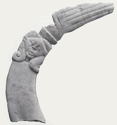 "Clapper" or wand of Hathor made from the tusk of a hippopotamus , an animal once native to Syria-Palestine. The goddess is shown here in Egyptian fashion, with cow's ears and wearing a large wig and collar. Above her head extends a hand. A matching pair of such objects are thought to have been "clapped" above a priest's head in Egyptian religious ceremonies. 