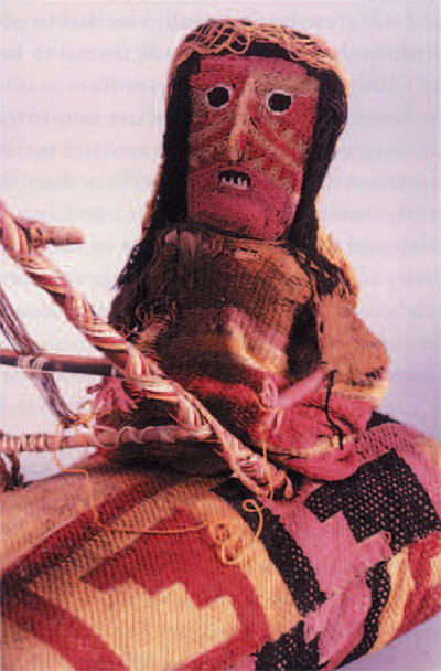 The weaving lady wears a woven garment and a twined openwork scarf. She sits on a pillow covered with a brocaded textile. The fabrics of the figure and pillow are supported by underlying bundles of leaves and plant fibers. The loom frame is made of lengths of reed decorated with plaited yarns, and the tree is fashioned from a bundle of reeds or grasses wrapped with yarn. 