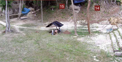 View of archaeological site, showing excavated stairs and a covered section with people digging in the middle of an open area.