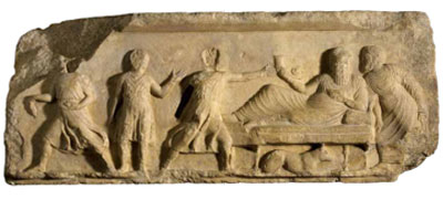 Frieze showing a banquet scene with a dog lying beneath the table.