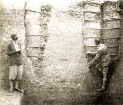 Katharine and Leonard Woolley measure Ur drainage pipes, made from stacked pottery cylinders, 1929–1930.