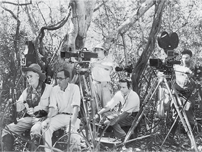 A staged photograph of the crew includes, from left to right: George Rawls (actor), David Crosby (camera and director) in front of Debrie Parvo silent movie camera, "operated" by John S. Clarke, Ainslee Davis sitting low with the mixer, and Arthur Rossi (2nd cameraman), with Mitchell sync sound camera (UPM image #25717).