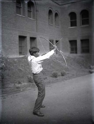 Tony Tillohash, a student at the Carlisle Indian School, outside the Penn Museum demonstrating the use of a bow and arrow, 1909. He was a vital collaborator with Edward Sapir at the Museum. (UPM image #11937)