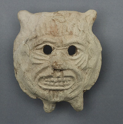 Terracotta demon mask of an animal face bearing its teeth.