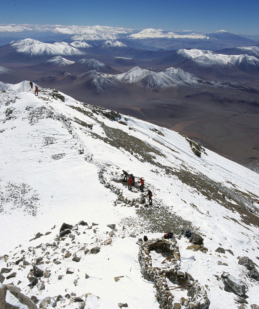 A small team of people on a snowy mountian peak.