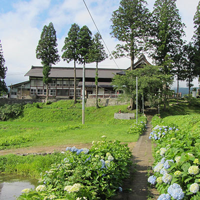 A temple surrounded by grass, flowers, and tress.