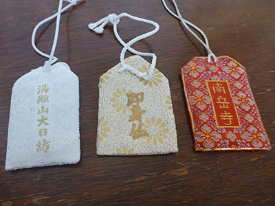 Tea bag shaped amulets made of robe material, embroidered characters in a line down the center.