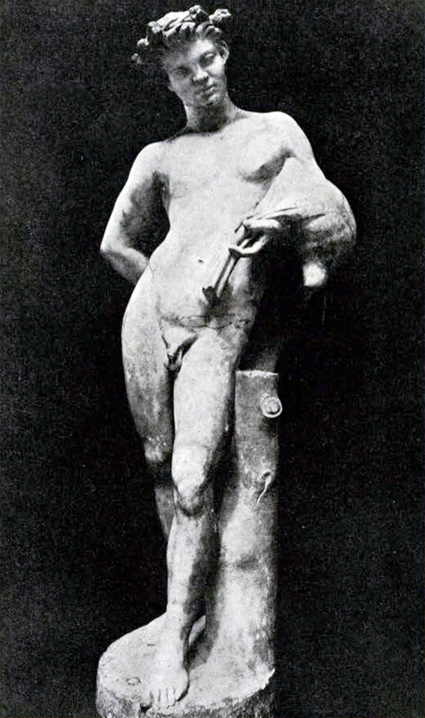 Marble statue, mostly restored material, of a naked faun holding a wineskin over his left arm, with his right arm held behind his back.