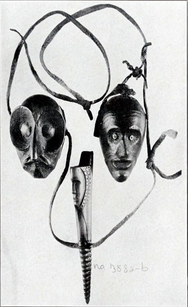 Two wood-carved faces strung on necklaces and one powder charger carved out of antler.
