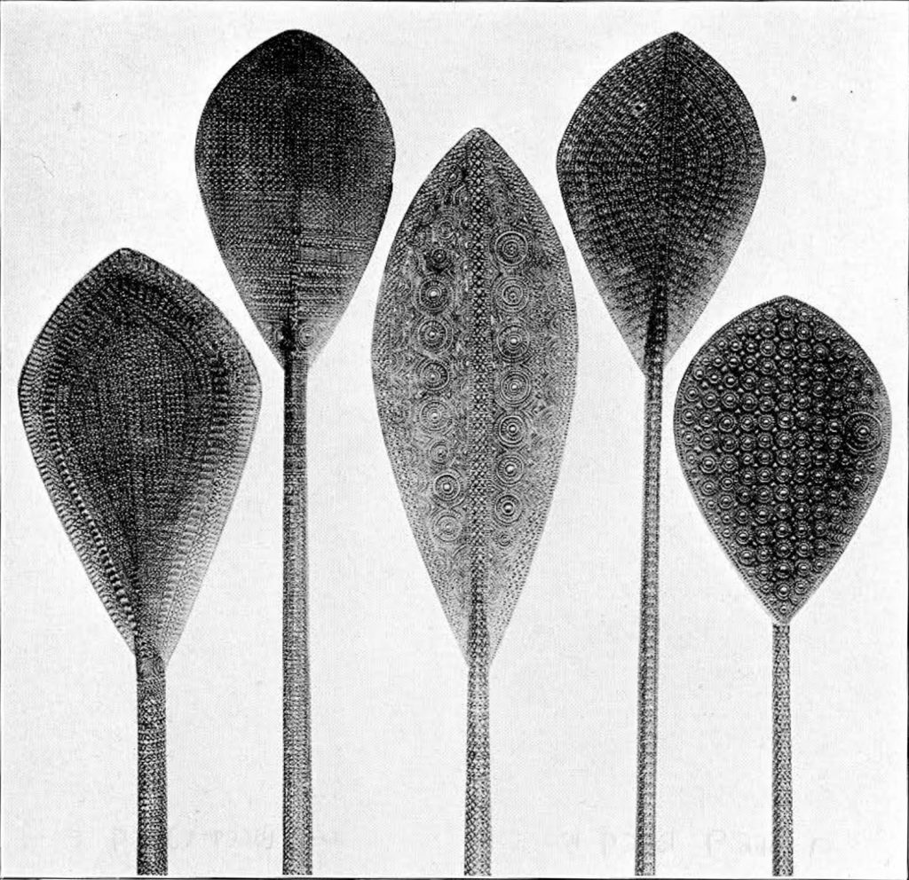 Five paddles with intricate carved patterns in lines and circles
