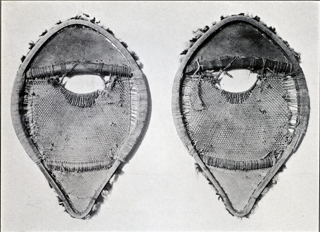 A pair of round snowshoes with tufts of fabric on the outside edges