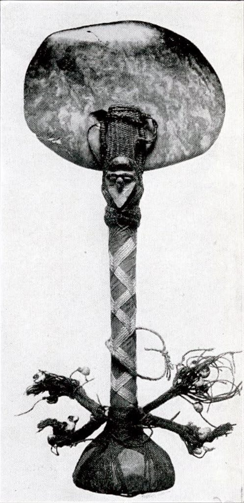 A ceremonial axe with cord wrapped handle in a braid pattern, fabric tassels, and a round flat jadeite blade