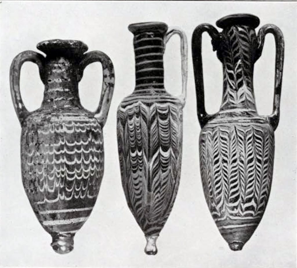 Three core-form variegated small amphoras, middle amphora has one handle, left and right have two