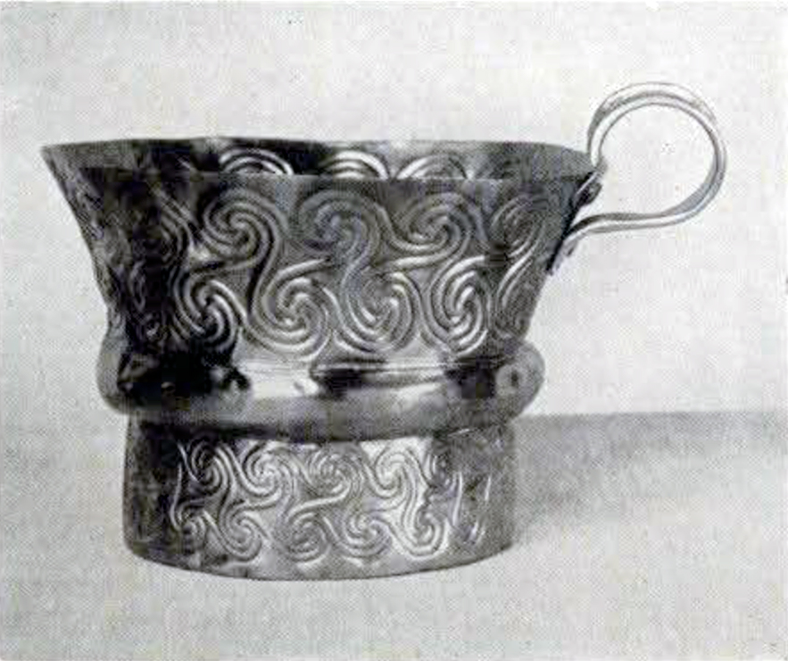A gold cup with a spiralform decoration and small handle