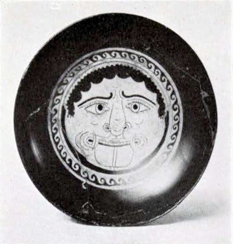 Gorgoneion face with tongue out encircled by a band of wave pattern