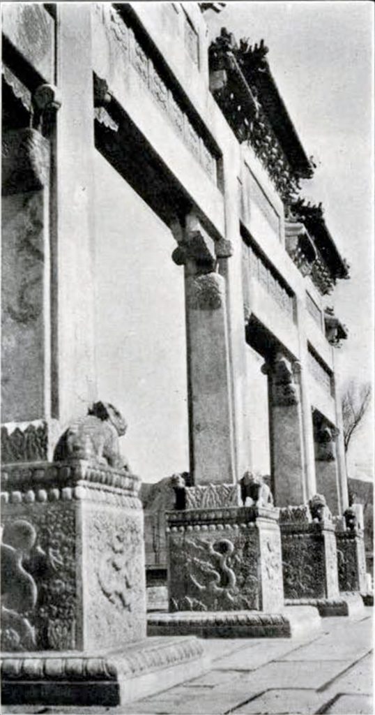 A white marble gateway with square columns and carved decoration