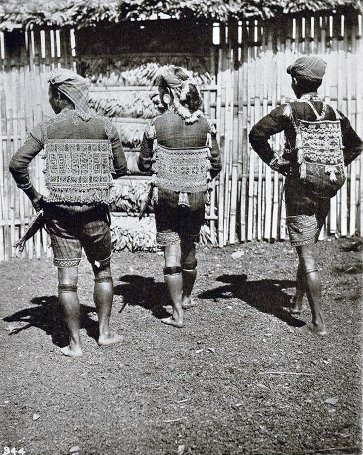 Three men from behind showing detailed embroidery on their pags and shirts