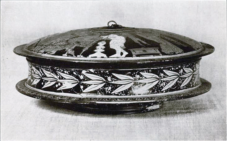 Red figure pyxis from the side, showing the vertically symmetrical shape and a band of leaf pattern