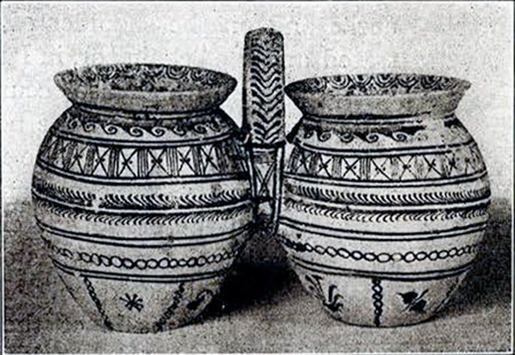 Two identical conjoined vases with a handle between