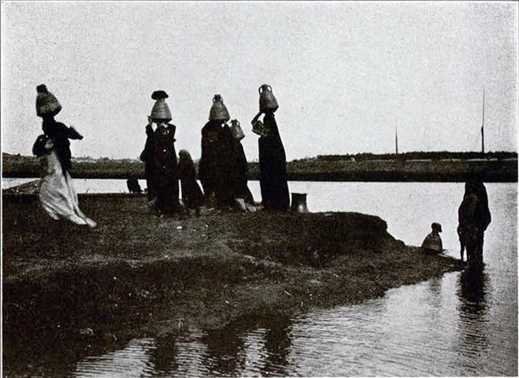 A group of women filling their water jars and carrying them on their heads