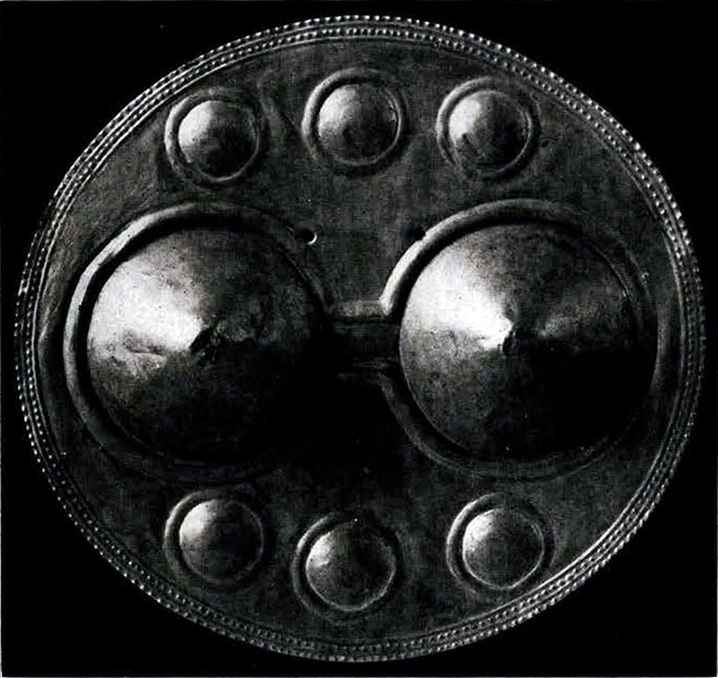 A circular breastplate with three lateral bosses on the top and bottom