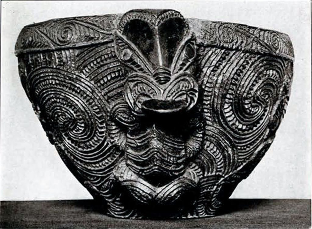 Round wooden bowl with large spirals and human figures as handles, handles facing the camera