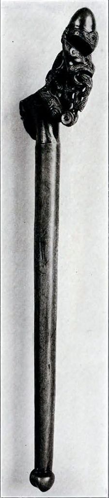 The handle of an adze with an intricate human figure at the head