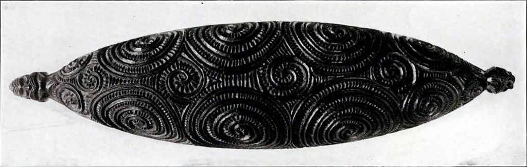 Lid of a wood carved box with spirals of different sizes and figures at either end