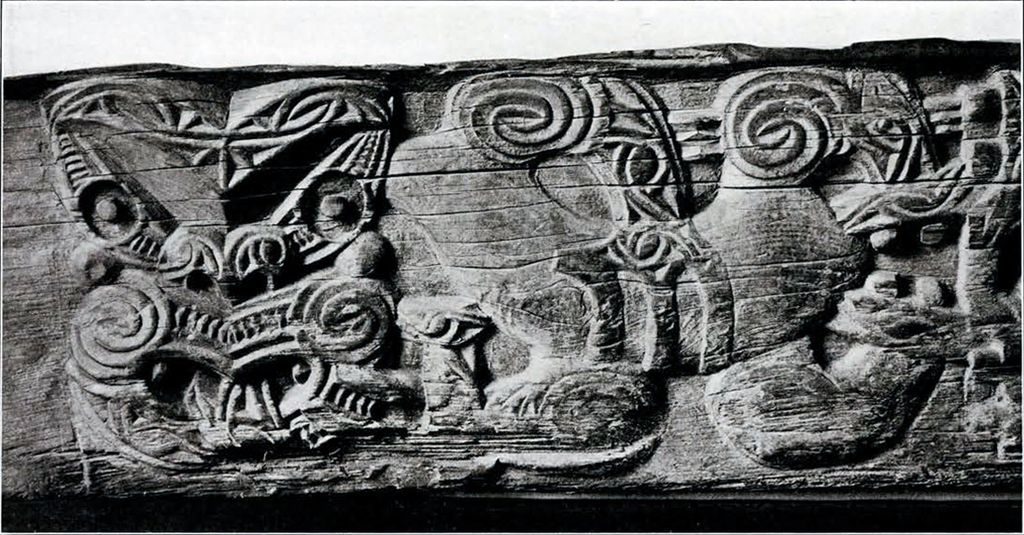 A close up of one side of the carved board, showing the stylized human face and body
