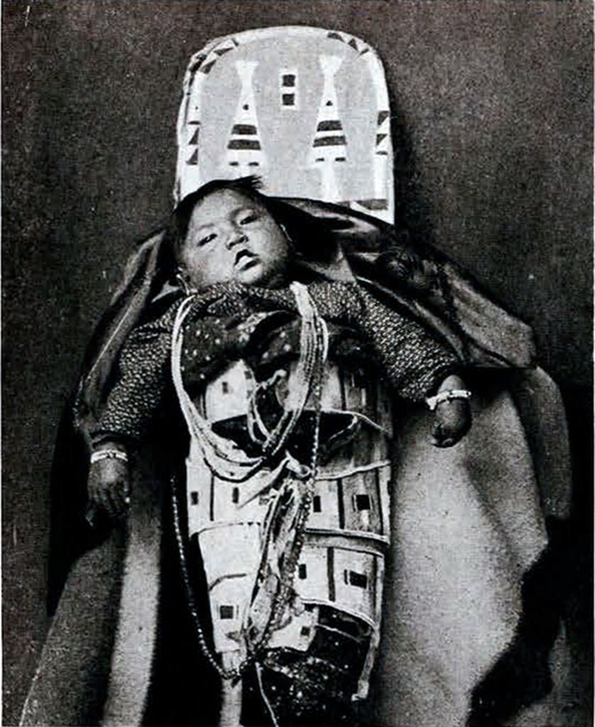 A baby in a papoose in a cradle